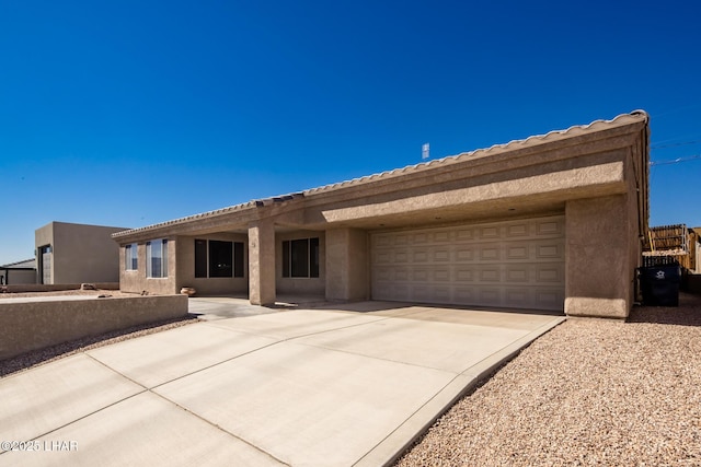 view of front of home featuring concrete driveway, an attached garage, a tiled roof, and stucco siding