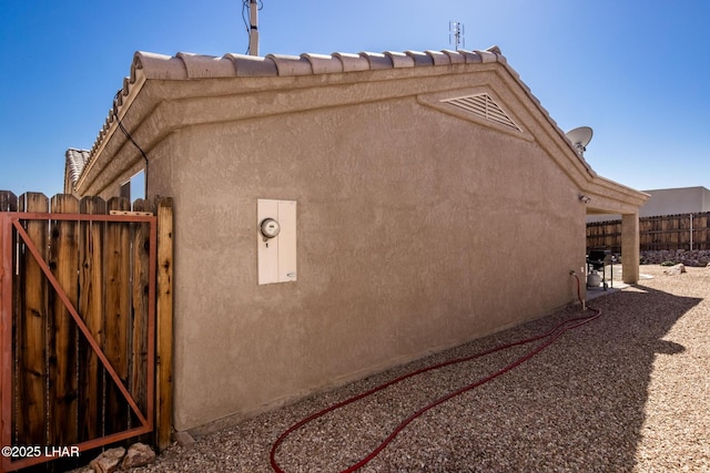 view of home's exterior with fence, a gate, and stucco siding