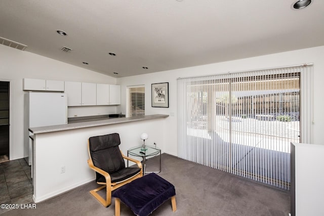 living area with visible vents, vaulted ceiling, and dark colored carpet