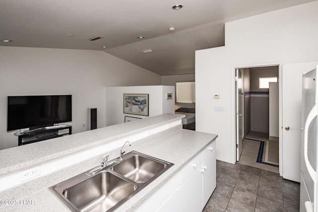 kitchen featuring a sink, visible vents, white cabinetry, vaulted ceiling, and light countertops