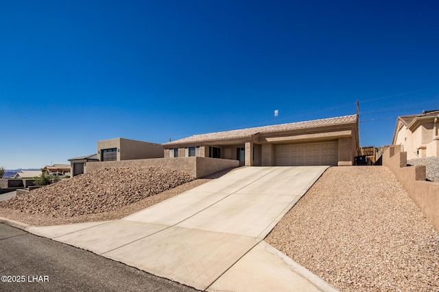 view of front of house featuring concrete driveway, an attached garage, fence, and stucco siding