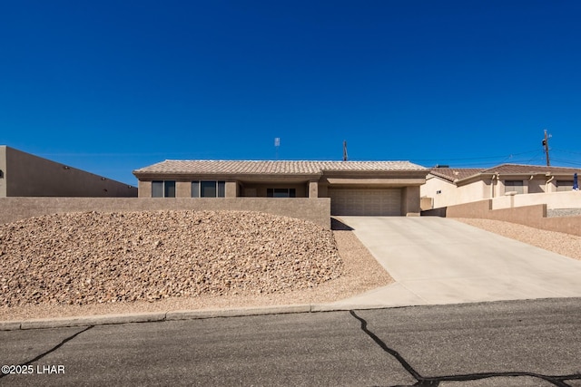 view of front of house featuring concrete driveway, a tiled roof, an attached garage, and stucco siding