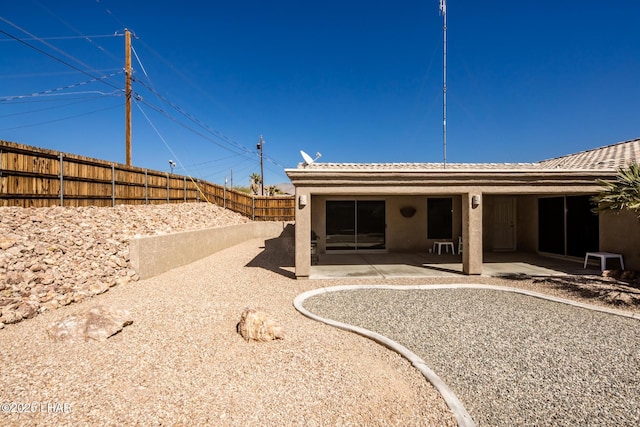 back of property with a fenced backyard, a patio, and stucco siding