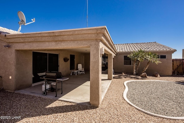 rear view of house with a patio, fence, a tiled roof, and stucco siding