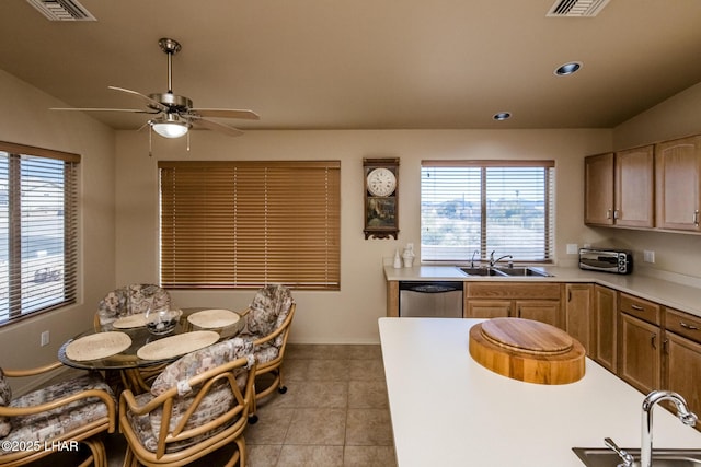 kitchen featuring dishwasher, light countertops, a sink, and visible vents