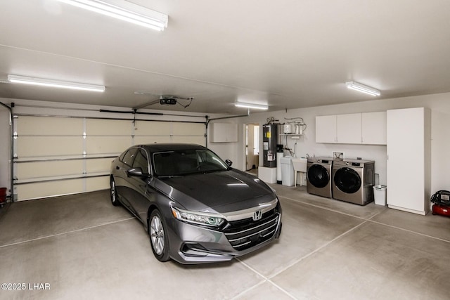 garage featuring water heater, washing machine and dryer, and a garage door opener