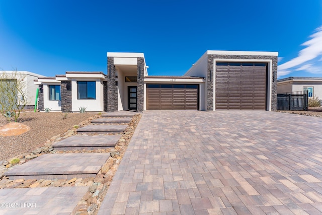 view of front facade with stone siding, decorative driveway, an attached garage, and stucco siding