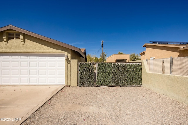 view of side of property with a garage, fence, and stucco siding