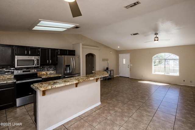 kitchen with light tile patterned floors, visible vents, a ceiling fan, a breakfast bar, and stainless steel appliances