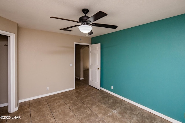 unfurnished bedroom featuring tile patterned flooring, a ceiling fan, and baseboards