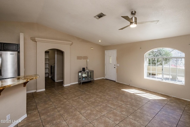 unfurnished living room featuring ceiling fan, visible vents, arched walkways, and vaulted ceiling