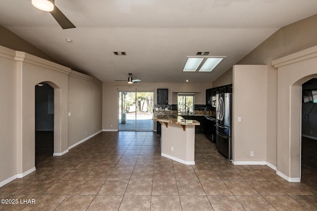 kitchen featuring stainless steel fridge, visible vents, arched walkways, and ceiling fan