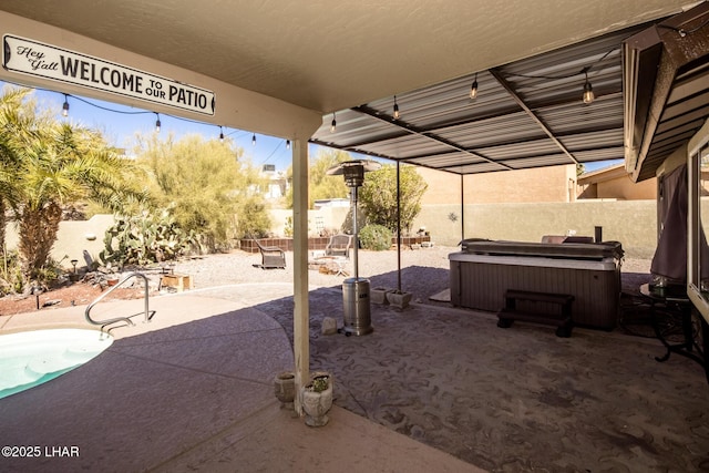 view of patio / terrace with a hot tub and fence