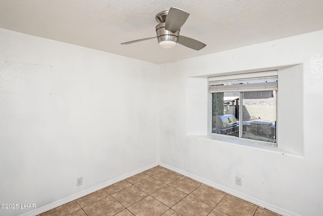 empty room with light tile patterned floors, ceiling fan, baseboards, and a textured ceiling