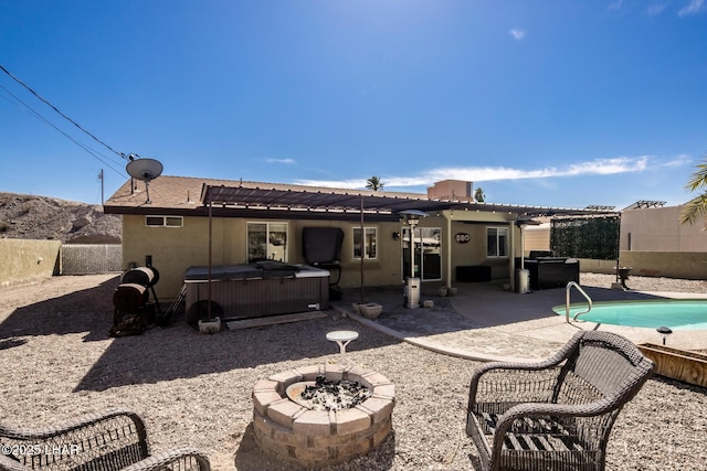 back of property featuring a fenced in pool, a patio, stucco siding, a hot tub, and a fire pit