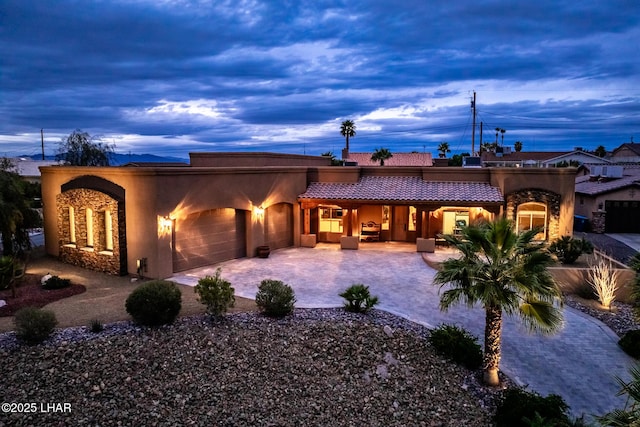 view of front of property featuring a garage, decorative driveway, a tile roof, and stucco siding