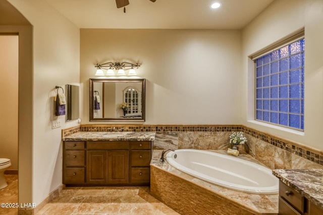 bathroom with toilet, ceiling fan, vanity, a bath, and recessed lighting