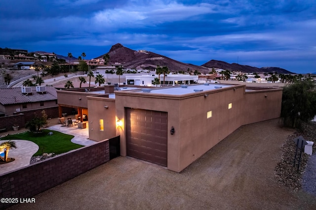 view of front of home featuring a mountain view, a garage, driveway, stucco siding, and a patio area