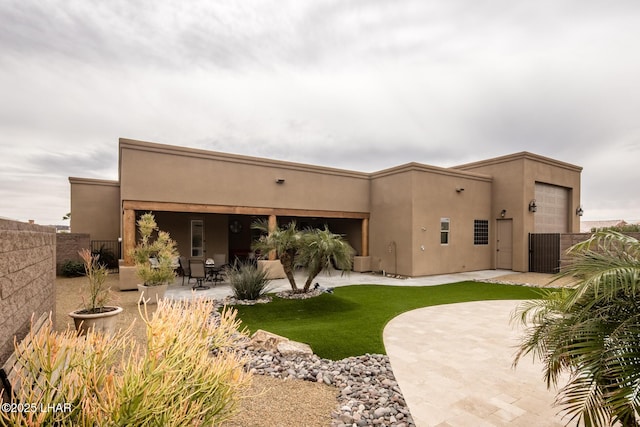 rear view of house featuring a yard, a patio area, fence, and stucco siding