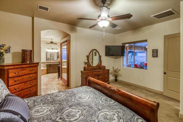 bedroom featuring arched walkways, ceiling fan, ensuite bath, and visible vents