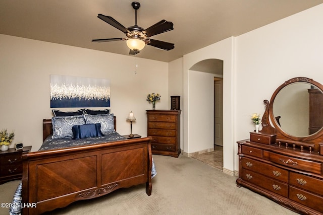 bedroom with a ceiling fan, arched walkways, and light carpet