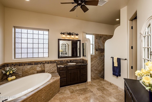 bathroom with stone tile floors, visible vents, vanity, a bath, and walk in shower