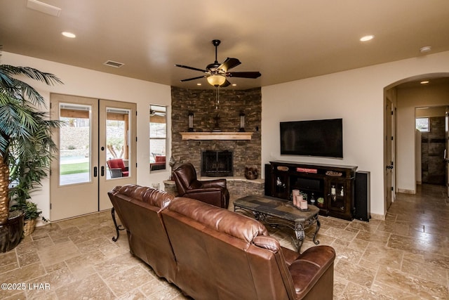 living room with arched walkways, ceiling fan, stone tile flooring, and recessed lighting