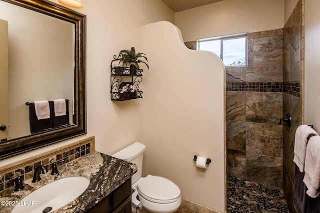 full bathroom with toilet, a tile shower, and vanity