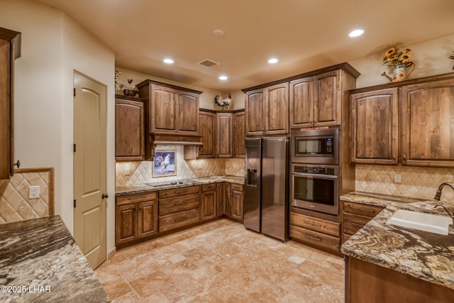 kitchen with visible vents, under cabinet range hood, stainless steel appliances, stone counters, and a sink