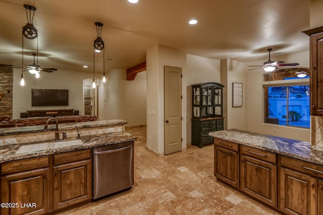 kitchen with stone counters, a sink, open floor plan, hanging light fixtures, and stainless steel dishwasher