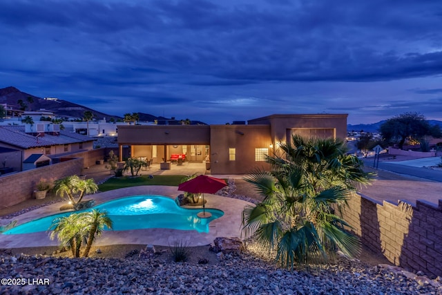 pool at dusk featuring a fenced backyard, an outdoor pool, and a patio