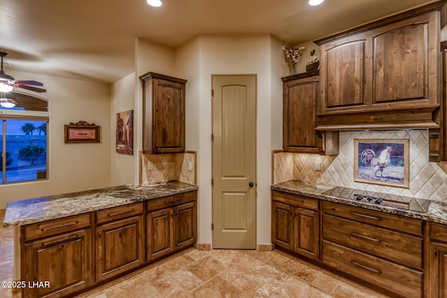 kitchen featuring a ceiling fan, black electric stovetop, decorative backsplash, and dark stone countertops