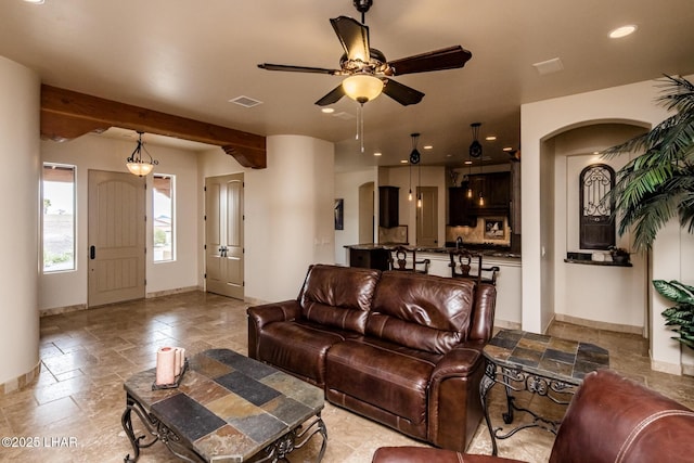 living area featuring baseboards, visible vents, arched walkways, and stone tile flooring