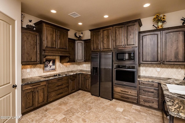 kitchen featuring stainless steel appliances, stone counters, visible vents, and dark brown cabinetry