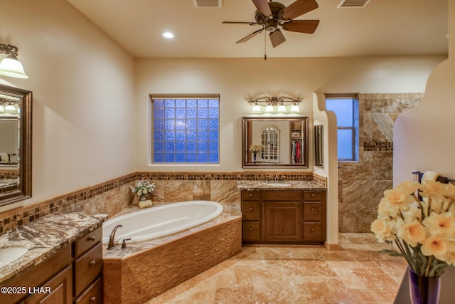 bathroom with two vanities, visible vents, a ceiling fan, a sink, and a bath