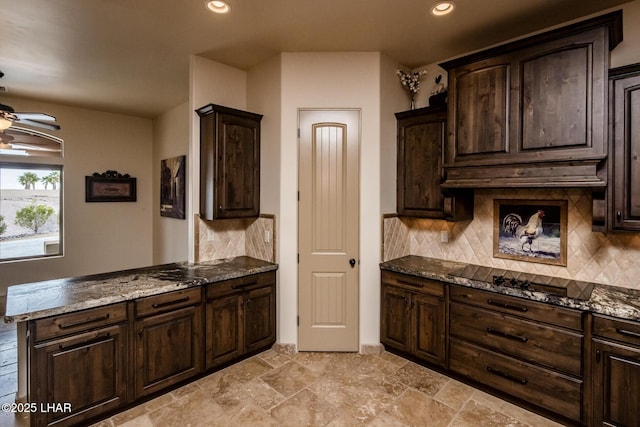 kitchen with a ceiling fan, dark stone countertops, dark brown cabinets, under cabinet range hood, and black electric cooktop