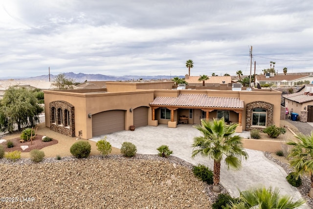 view of front of property with decorative driveway, a mountain view, an attached garage, and stucco siding