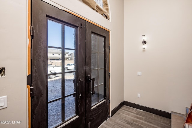 entryway with french doors, wood finished floors, and baseboards