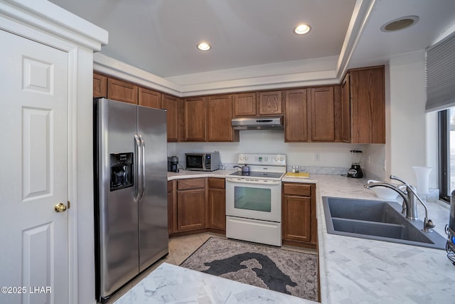 kitchen featuring brown cabinets, under cabinet range hood, a sink, appliances with stainless steel finishes, and light countertops