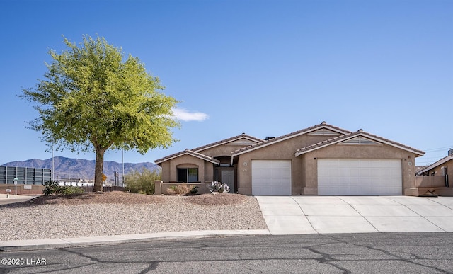 view of front of property featuring an attached garage, a tiled roof, stucco siding, driveway, and a mountain view