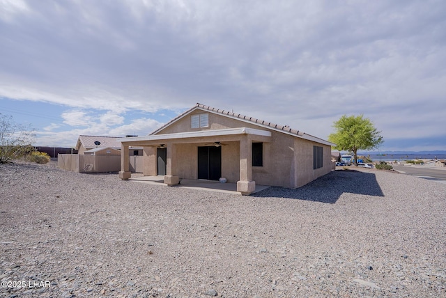 back of house with stucco siding, a ceiling fan, a patio, and fence