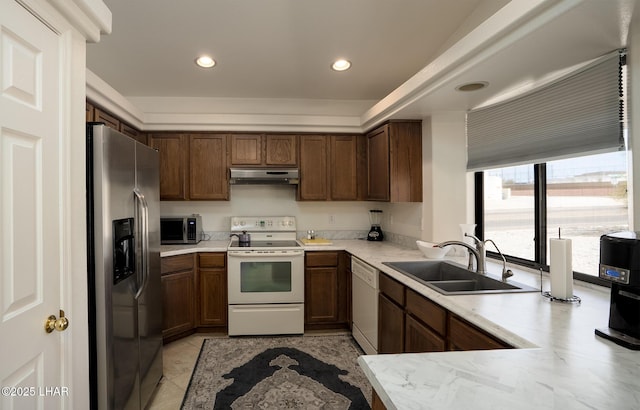 kitchen with under cabinet range hood, a sink, appliances with stainless steel finishes, light countertops, and light tile patterned floors