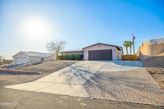 ranch-style house featuring fence, an attached garage, driveway, and stucco siding
