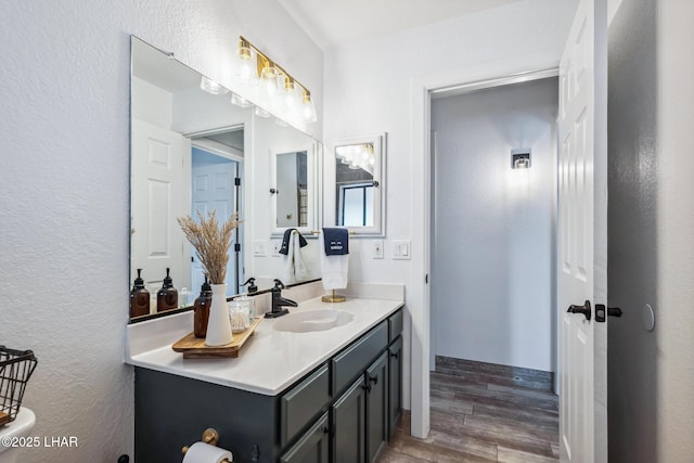 bathroom with wood finished floors, vanity, and a textured wall