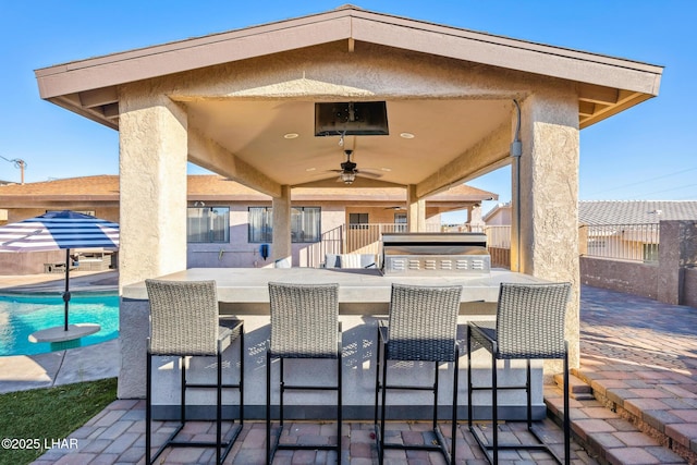 view of patio featuring an outdoor pool, outdoor wet bar, ceiling fan, and fence private yard