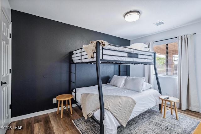 bedroom featuring wood finished floors, visible vents, and baseboards