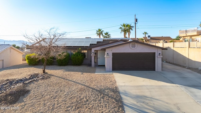 ranch-style house featuring solar panels, driveway, fence, an attached garage, and stucco siding