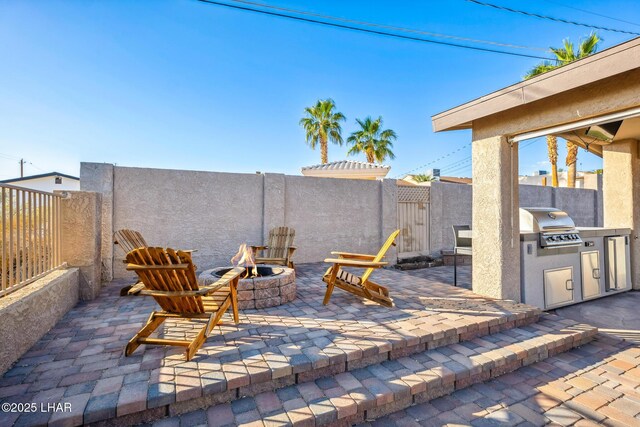view of patio / terrace featuring area for grilling, an outdoor kitchen, a fenced backyard, and an outdoor fire pit