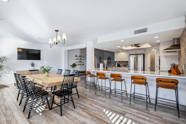 dining area with ceiling fan with notable chandelier, light wood-style flooring, visible vents, and recessed lighting