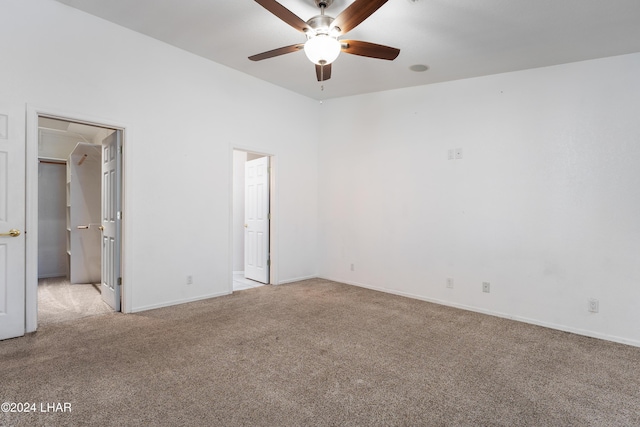 unfurnished bedroom featuring a walk in closet, light colored carpet, and ensuite bath